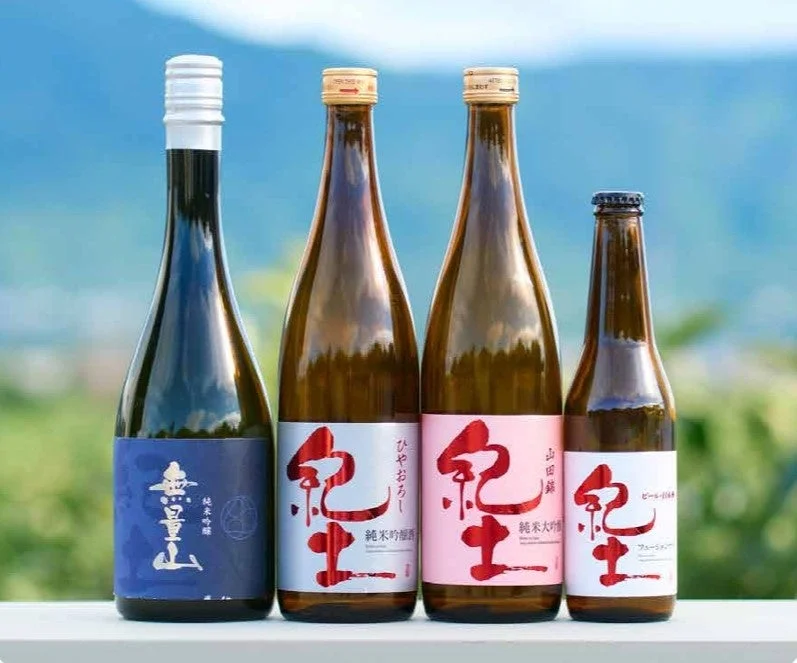 青い背景をバックに、4本の日本酒のボトルが並べられています。異なるラベルデザインとサイズで、様々な種類の「紀土」や「豊山」の日本酒が紹介されています。