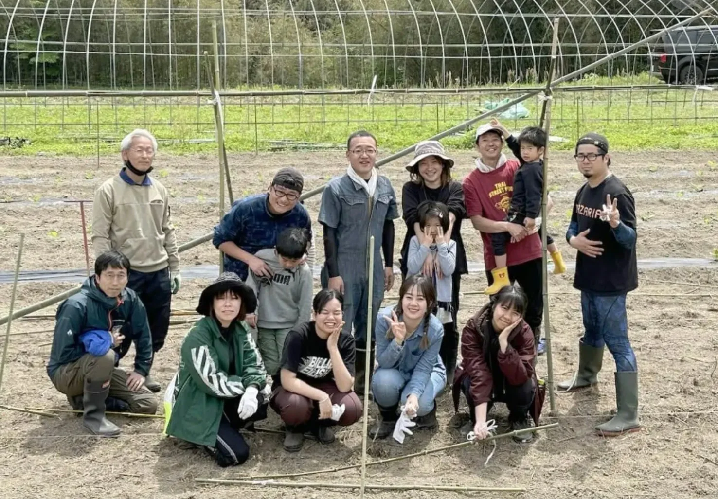 畑で多くの人々が集合写真を撮っている