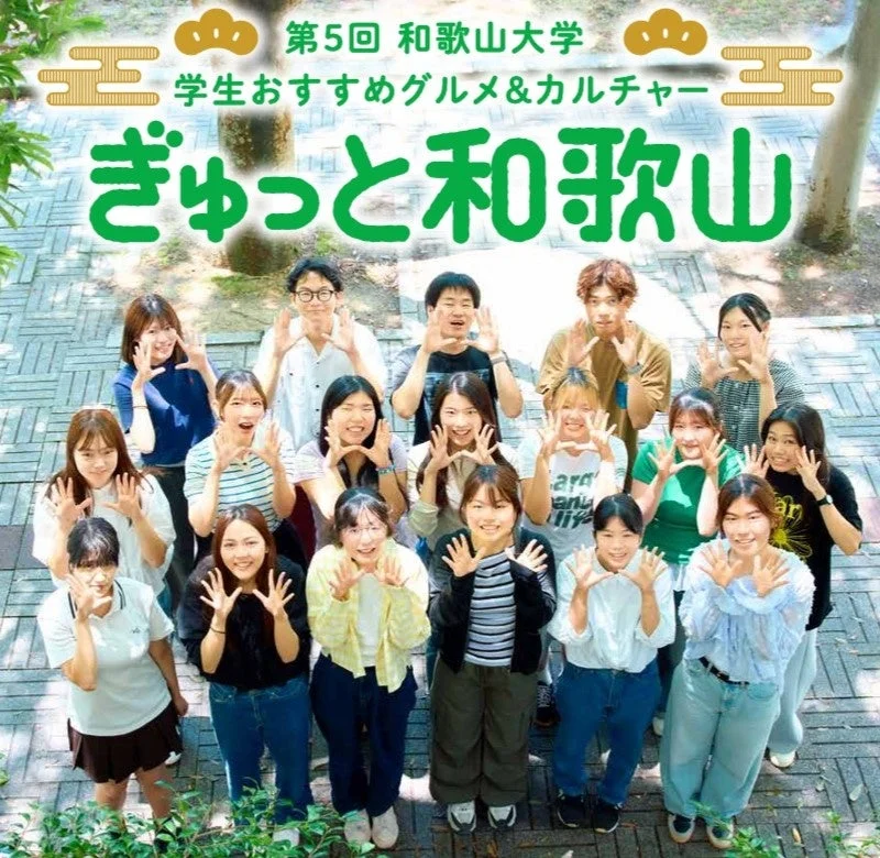 和歌山大学の学生たちが屋外で楽しそうにポーズをとっている集合写真です。「第5回 和歌山大学 学生おすすめグルメ&カルチャー ぎゅっと和歌山」というイベントの様子を伝えるビジュアルと考えられます。