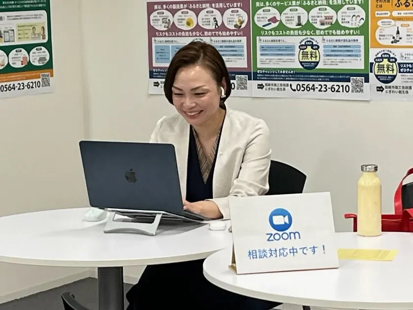 笑顔の女性がノートパソコンに向かい、オンラインでの相談対応をしている様子