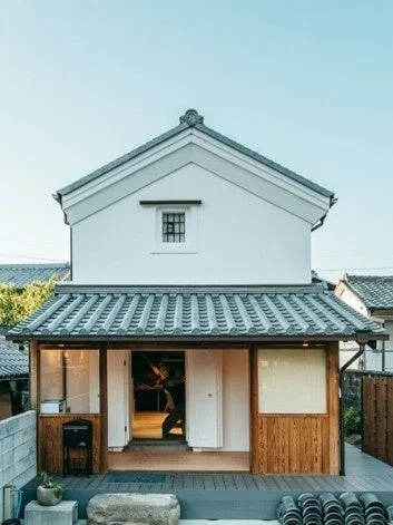 青い空の下に建つ、白い壁と瓦屋根が特徴的な和風建築の建物