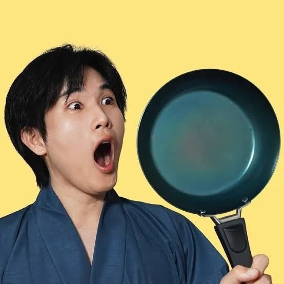 驚いた表情でフライパンを持つ男性