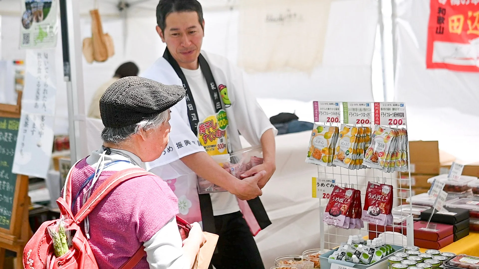 市場で販売員が客に説明する様子