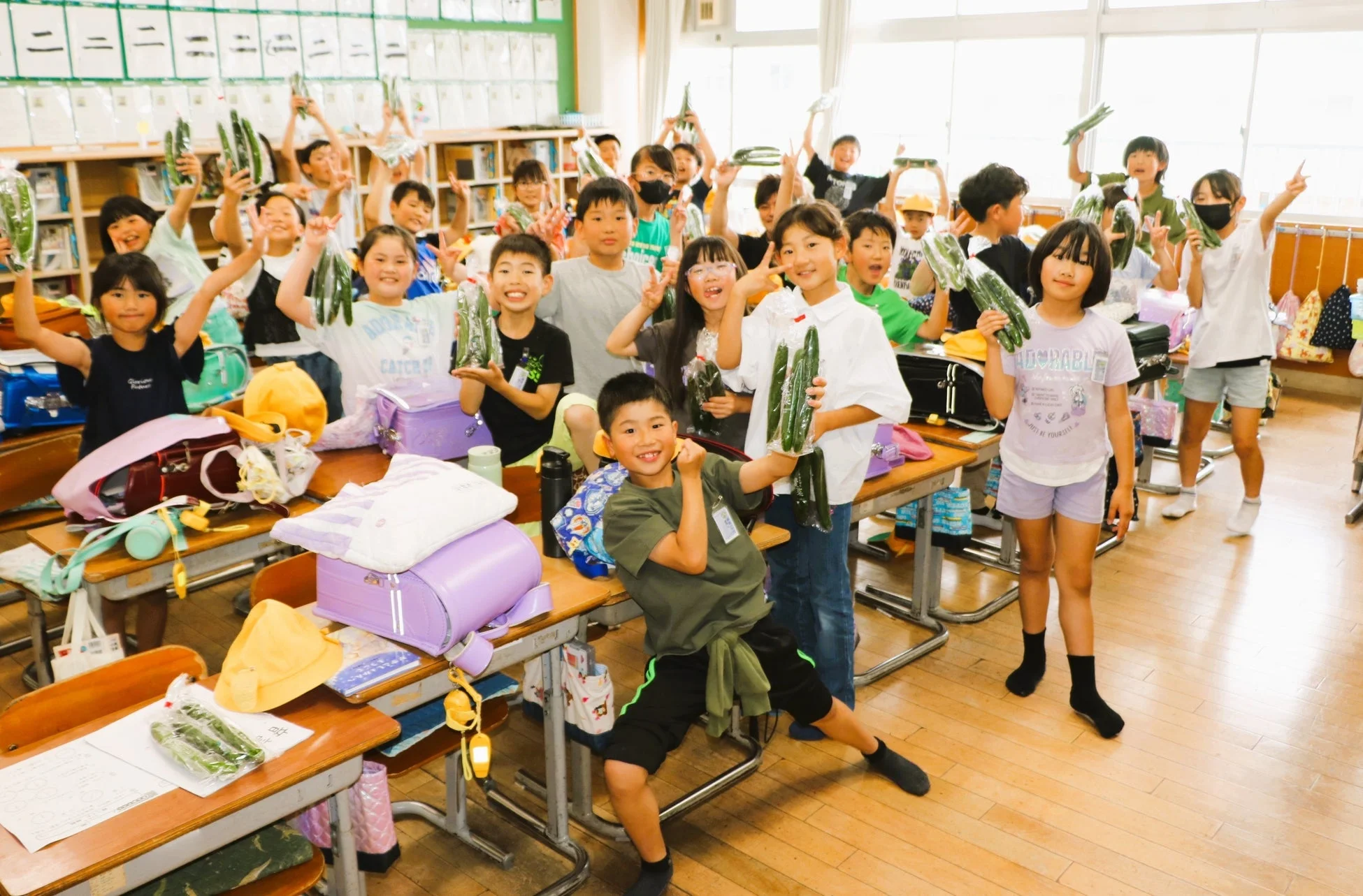 小学生が笑顔でキュウリを掲げている