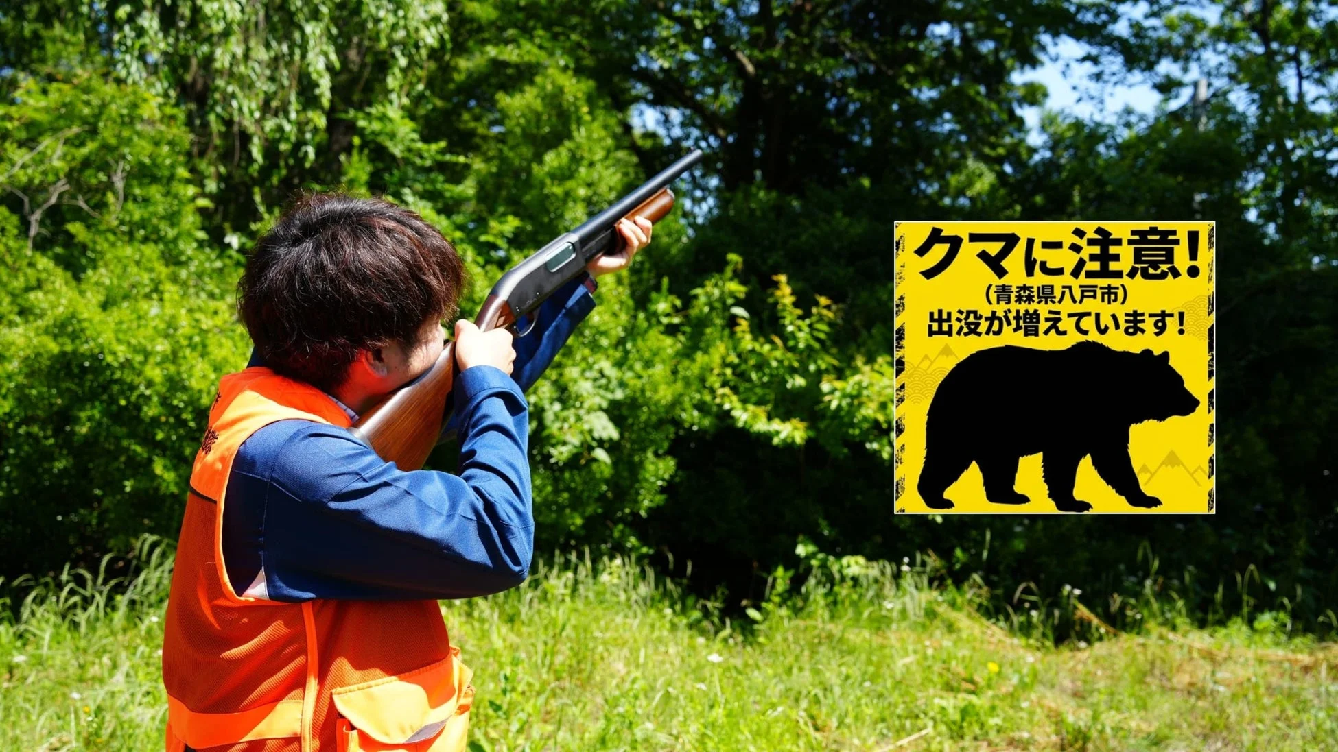 森林の中でオレンジ色のベストを着た人物が猟銃を構え、「クマに注意！(青森県八戸市)出没が増えています！」と書かれた警告看板が合成された画像