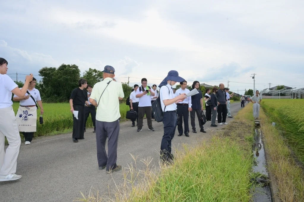 田んぼ脇で視察する人々